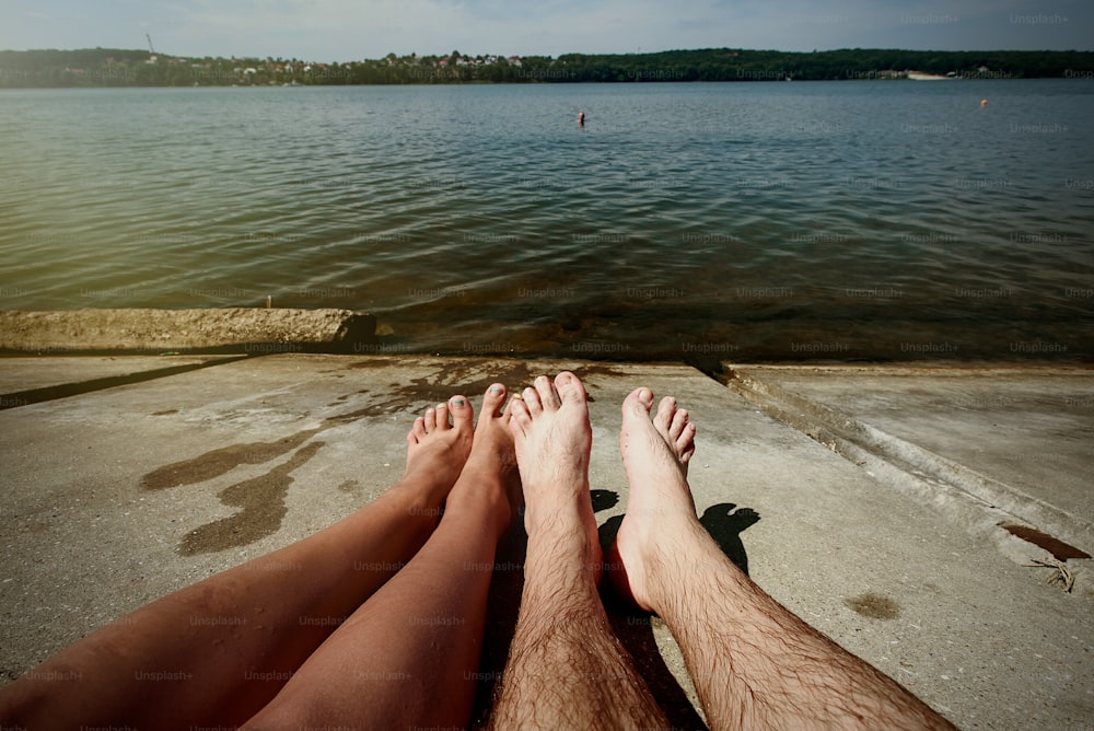 happy stylish couple legs, sunbathing at the beach, summer vacation, space for text