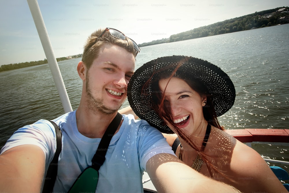 happy stylish couple taking selfie and sailing on a boat, having fun, summer vacation