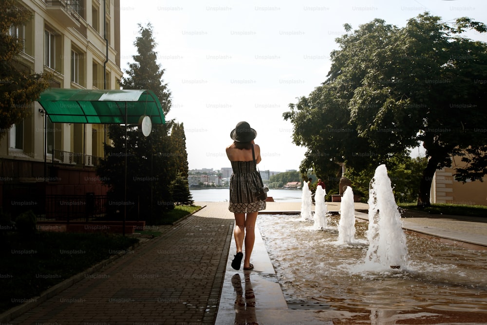 happy stylish woman hipster walking in city street near fountains, summer travel concept