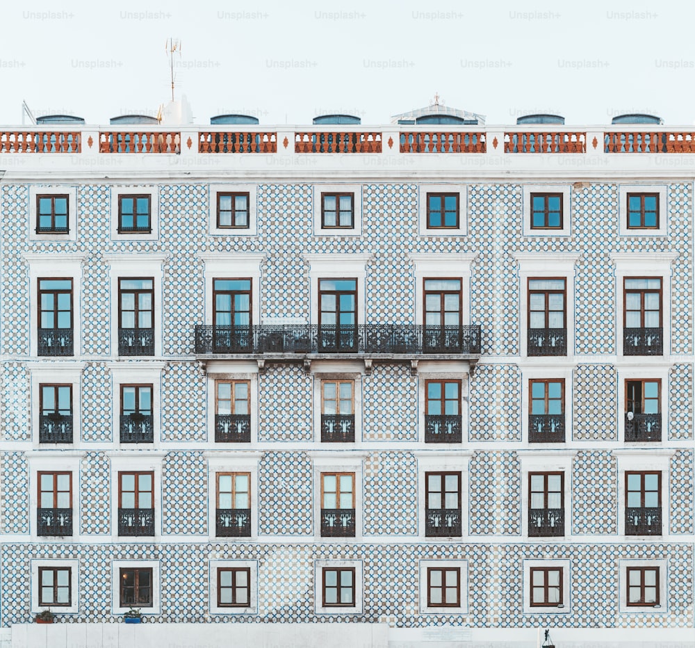 Facciata di una casa normale in Portogallo piastrellata con piastrelle azulejo, con un lungo balcone al centro; texture di un prospetto di un normale edificio residenziale a Lisbona con molte finestre