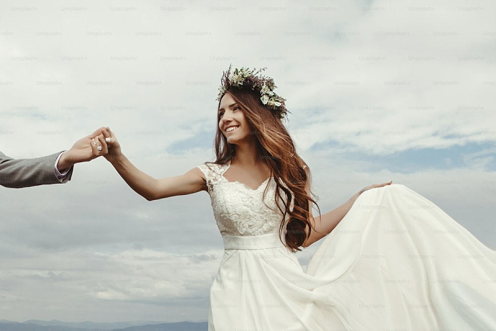 hermosa novia y novio tomados de la mano y bailando en el cielo y las nubes, momento de verdadera felicidad, ceremonia de lujo en las montañas con vista increíble, espacio para texto