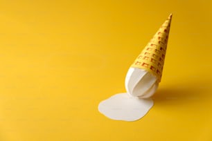 Cone de sorvete de baunilha de papel derretido no fundo amarelo. Espaço de cópia. Conceito de alimento criativo ou artístico