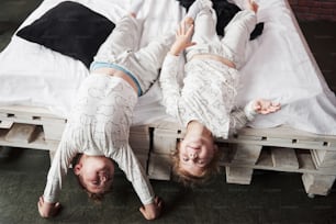 Niños felices jugando en el dormitorio negro. El niño y la niña, el hermano y la hermana juegan en la cama en pijama.