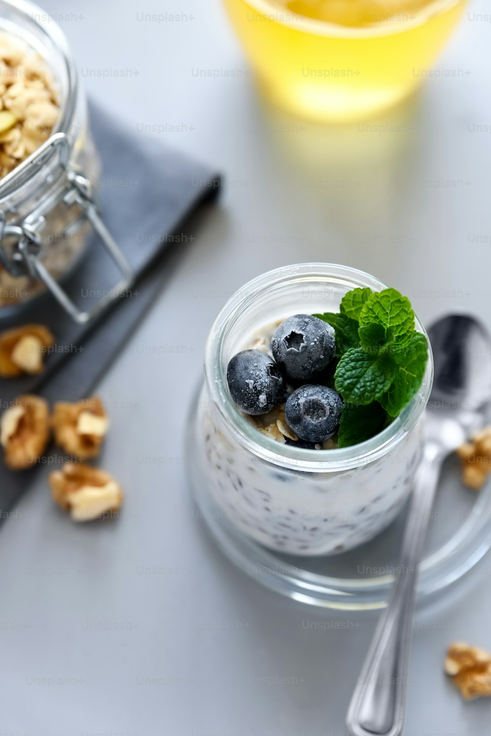Chia seed pudding with granola, blueberry, walnut and honey decorated mint leaves on gray background. Selective focus. Healthy eating or vegetarian food concept
