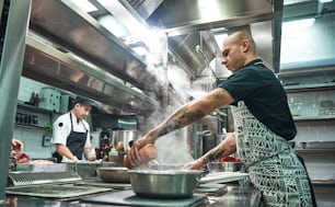 How to cook a meat Concentrated young chef in apron and cooks preparing food together in a restaurant kitchen. Cooking process