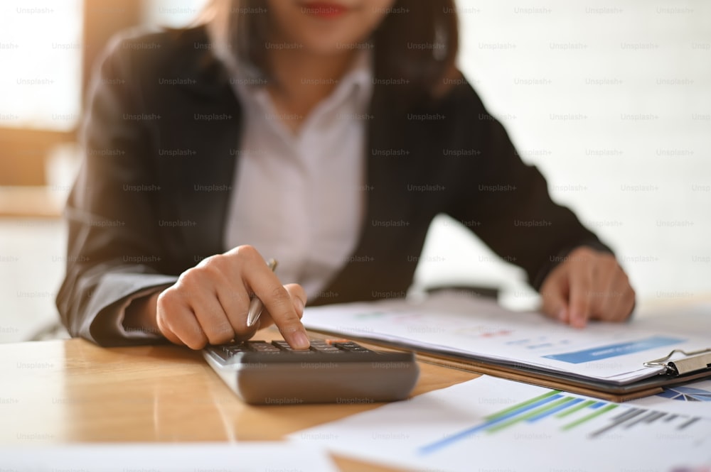 Financial businesswoman working with calculator and finance report.