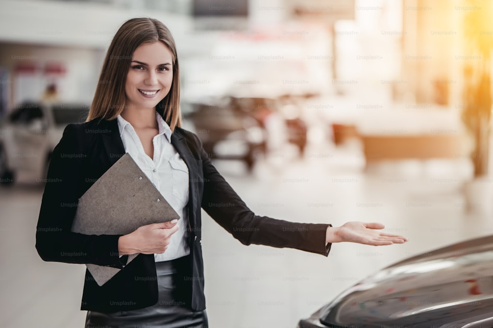 Professional female salesperson at car dealership.