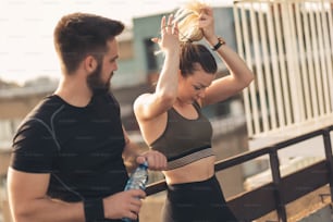 Young couple standing on a building rooftop terrace, getting ready for a workout