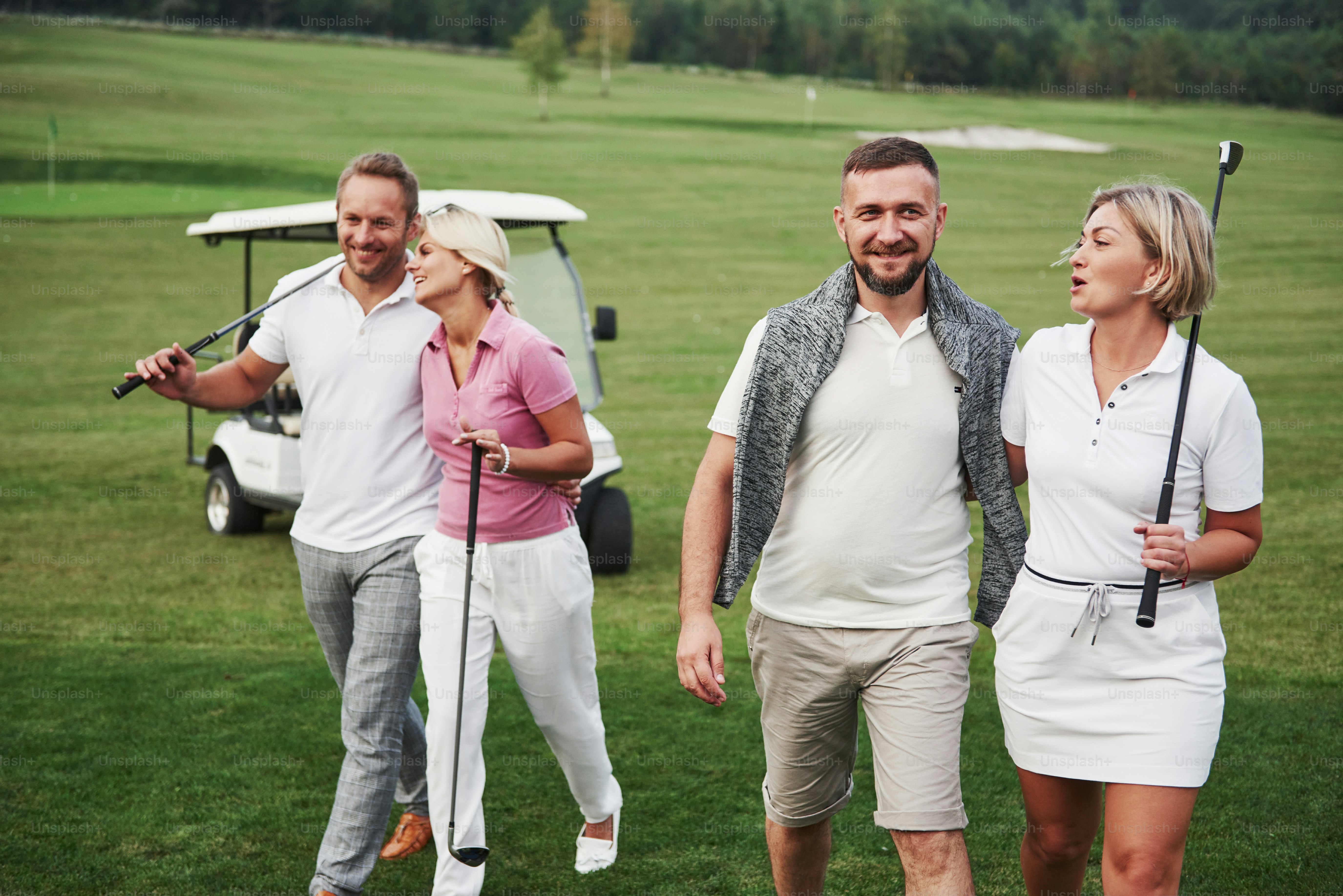 Casais jovens se preparando para brincar. Um grupo de amigos sorridentes chegou ao buraco em um carrinho de golfe