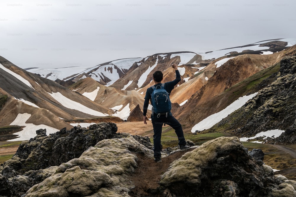 Reisende wandern in Landmannalaugar surreale Naturlandschaft im Hochland von Island, Skandinavien, Europa. Wunderschönes buntes Schneeberggelände, berühmt für Sommer-Trekking-Abenteuer und Outdoor-Wandern.
