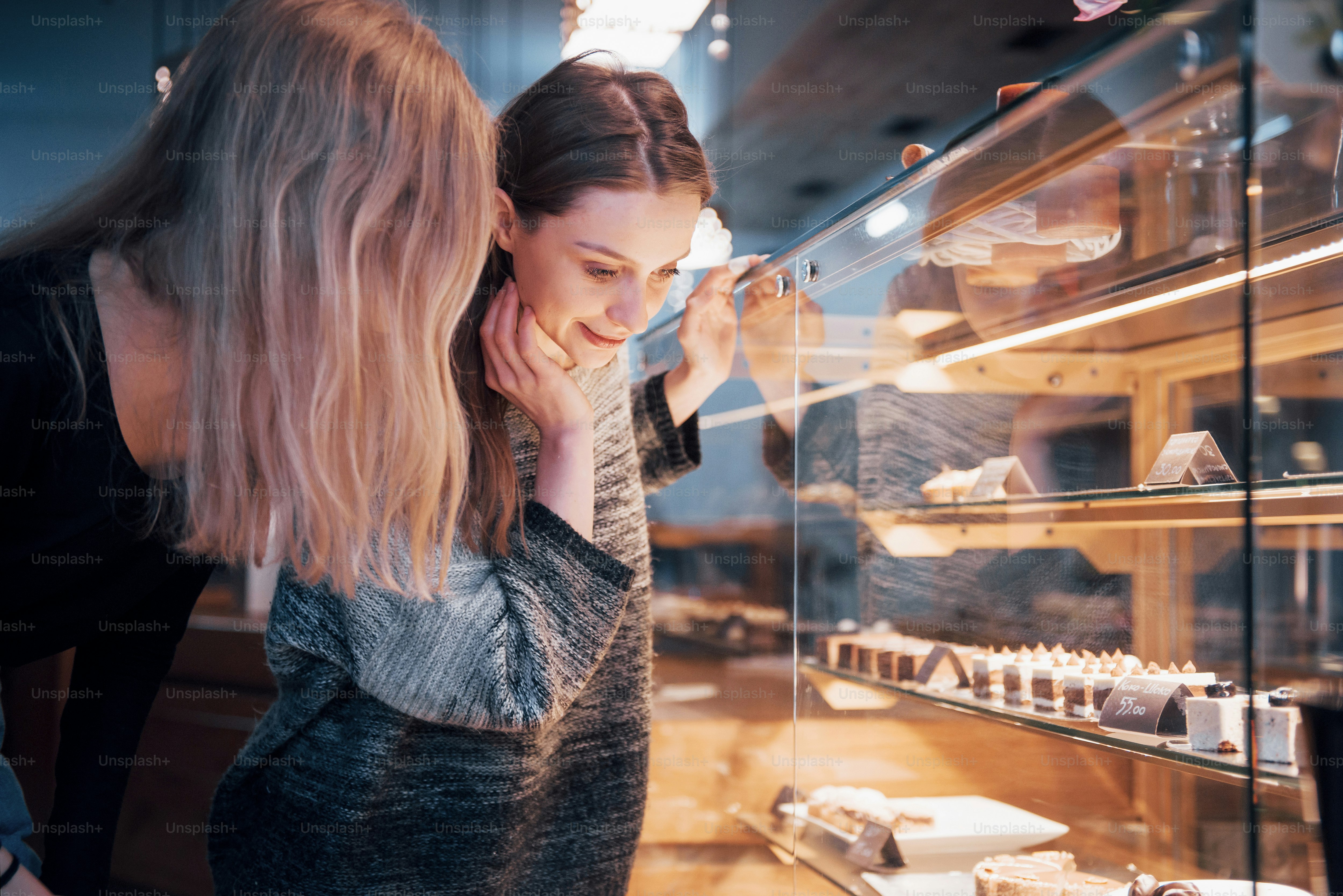 Two happy attractive girls choosing delicious ganaches, praline and chocolates.