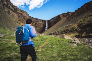 Man traveler hiking in Icelandic summer landscape at the Hengifoss waterfall in Iceland. The waterfall is situated in the eastern part of Iceland.