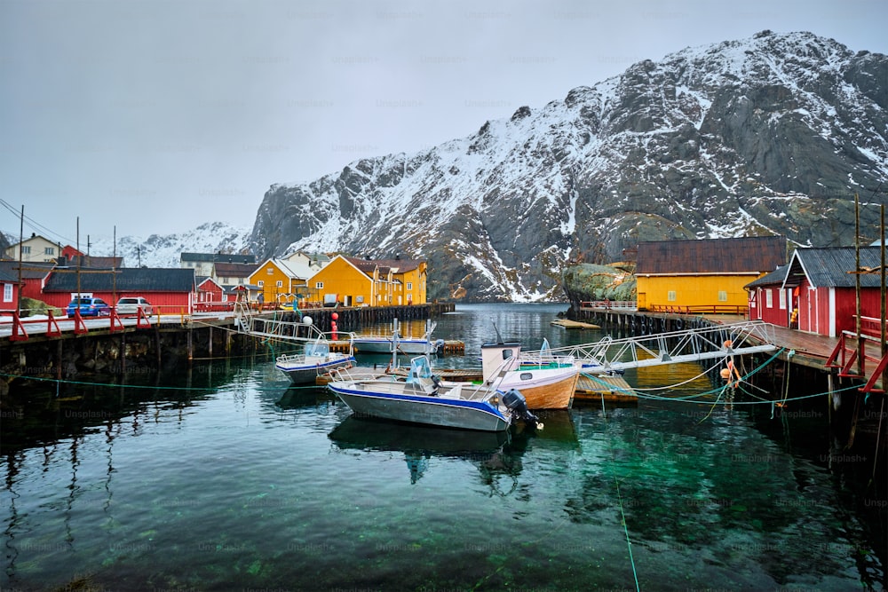 Pier with boats in Nusfjord authentic  fishing village in winter with red rorbu houses. Lofoten islands, Norway