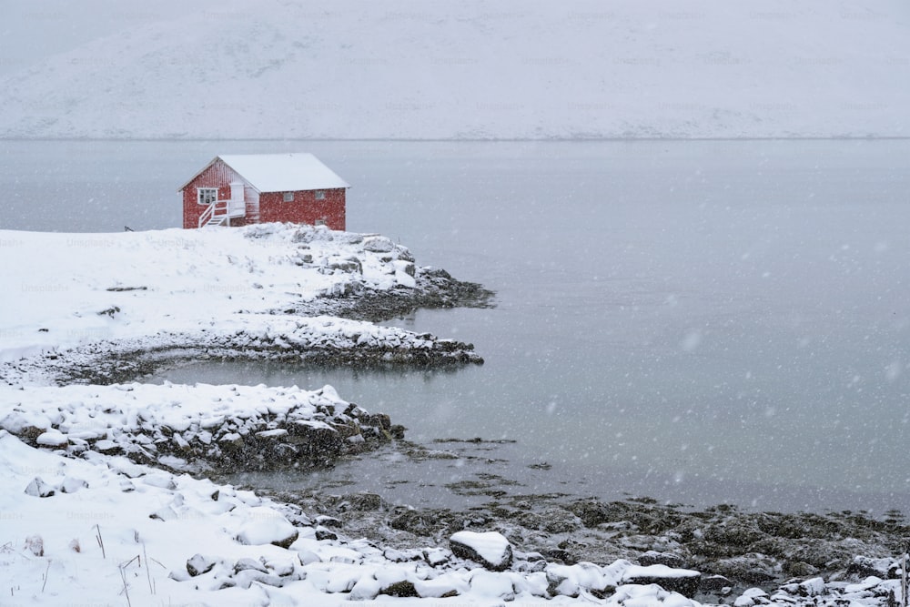 Maison traditionnelle rorbu rouge sur la rive du fjord avec de fortes chutes de neige en hiver. Îles Lofoten, Norvège