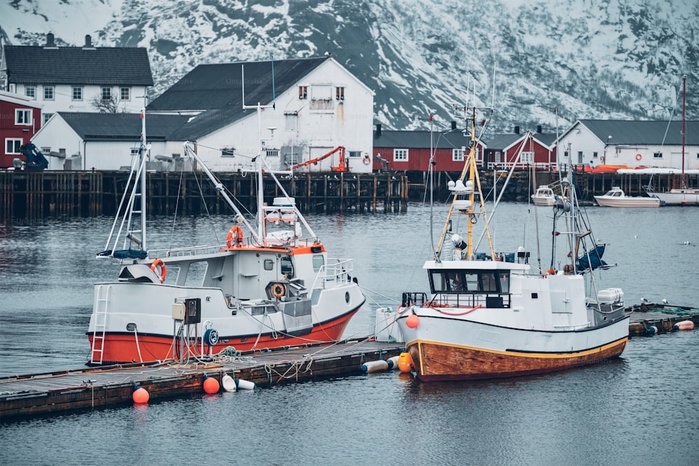 Molo con le navi nel villaggio di pescatori di Hamnoy sulle isole Lofoten, Norvegia con le case rosse del rorbu in inverno