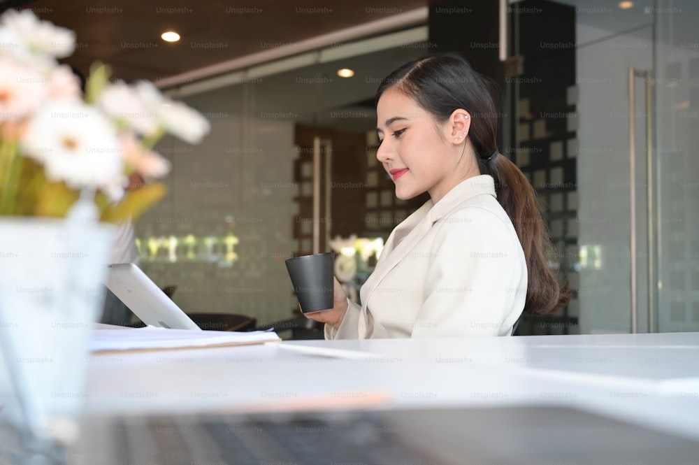 Asian businesswoman working with clip board and coffee on hands.