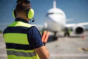 Meeting aircraft. Back view of aviation marshaller observing commercial jet and waiting for signaling