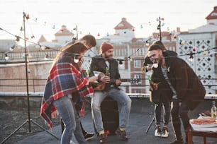 Cinque giovani amici fanno festa con birra e chitarra sul tetto.