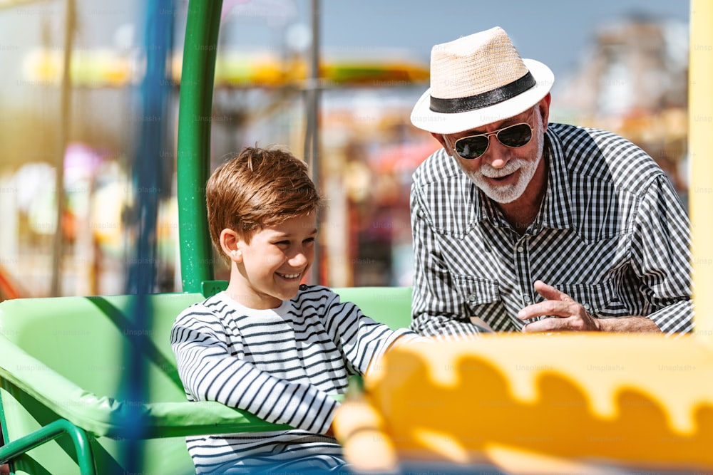 Abuelo y nieto divirtiéndose y pasando tiempo de buena calidad juntos en el parque de atracciones.