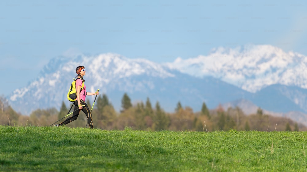 Menina caminhando nas montanhas com contrastes de primavera de prados verdes e neve nas montanhas