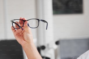 Focused photo. Woman hand holds the blue eyeglasses in the doctor cabinet.