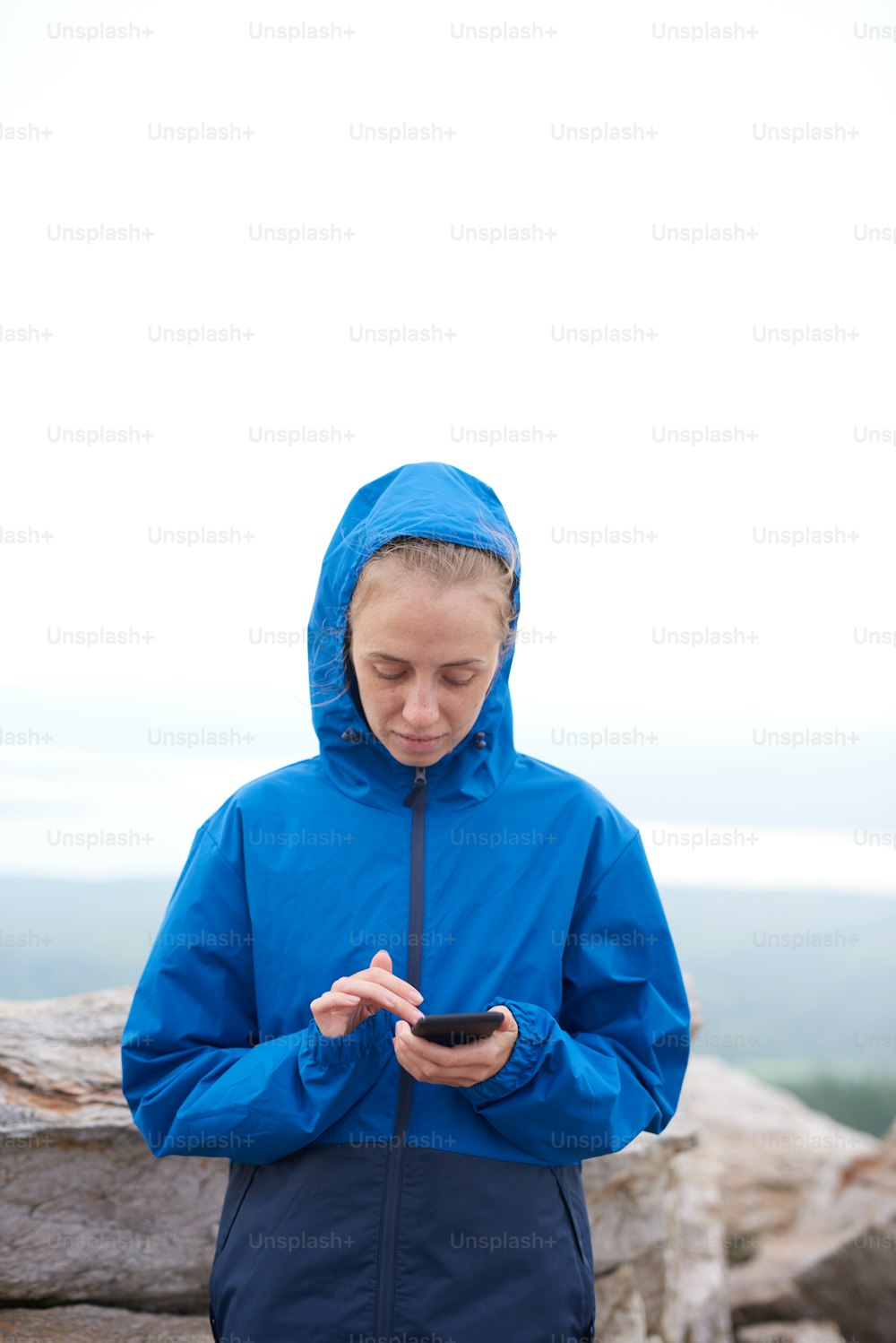 Portrait of pretty sports woman using smart phone on the top of the mountains after climbing with scenic view