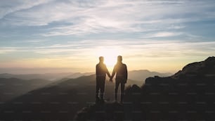 La pareja de pie en la montaña en el hermoso fondo del amanecer