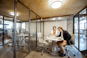 Homem e mulher de negócios que trabalham na sala de reuniões, ampla vista interior na sala com divisórias transparentes