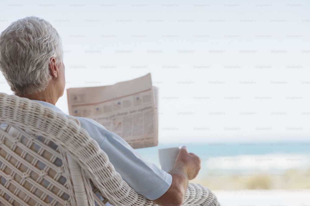 a man sitting in a chair reading a newspaper