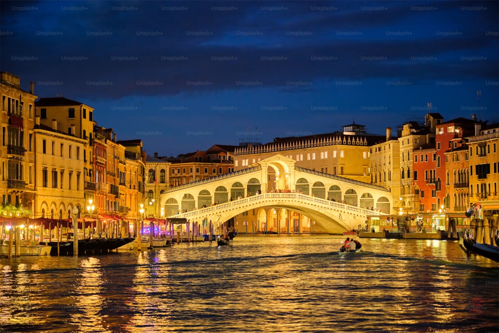 Berühmtes venezianisches Touristendenkmal Rialtobrücke (Ponte di Rialto) über den Canal Grande nachts beleuchtet in Venedig, Italien