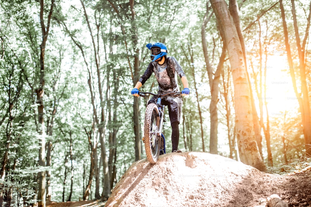 Professioneller, gut ausgestatteter Radfahrer, der auf dem Hügel steht, während er bergab im Wald fährt. Konzept einer Extremsportart und Enduro Radfahren