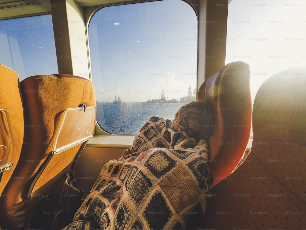 Mulher caucasiana dorme durante o transporte de ferry de cruzeiro - concep tof cansado para o estilo de vida de viagem e férias - sol na luz de fundo e oceano fora da janela
