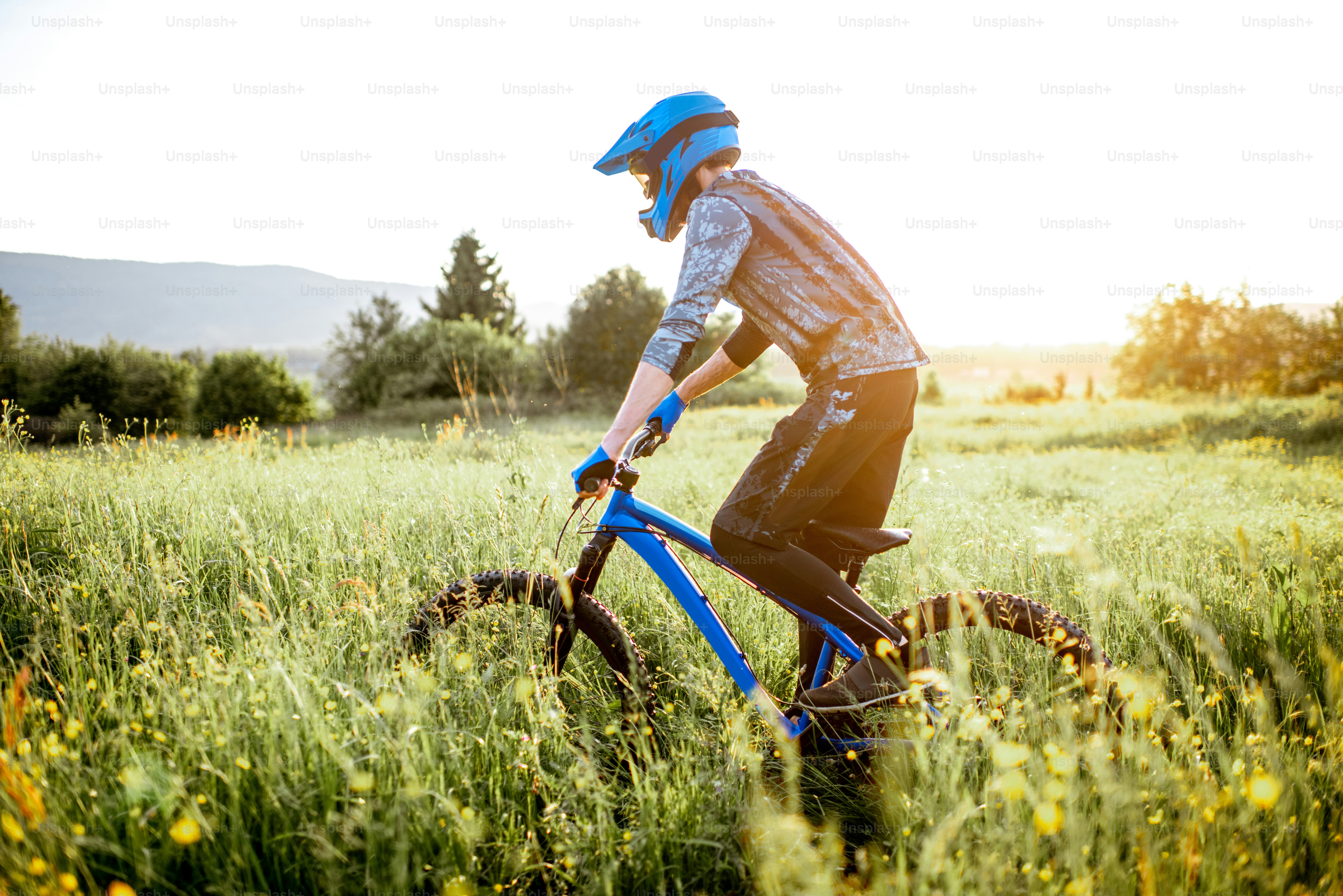 Professional well-equipped cyclist riding on the beautiful green field ...