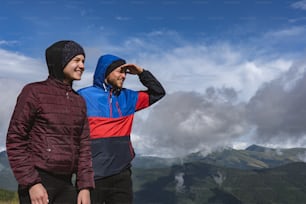 The happy man and woman standing on a mountain with a beautiful view