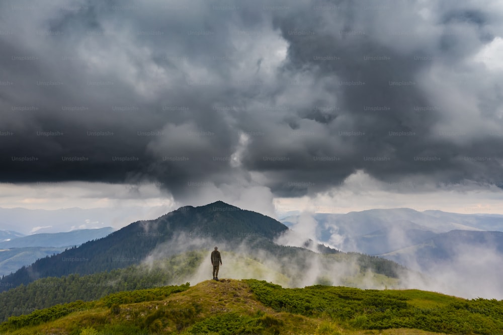 비오는 구름을 배경으로 산에 서있는 남자