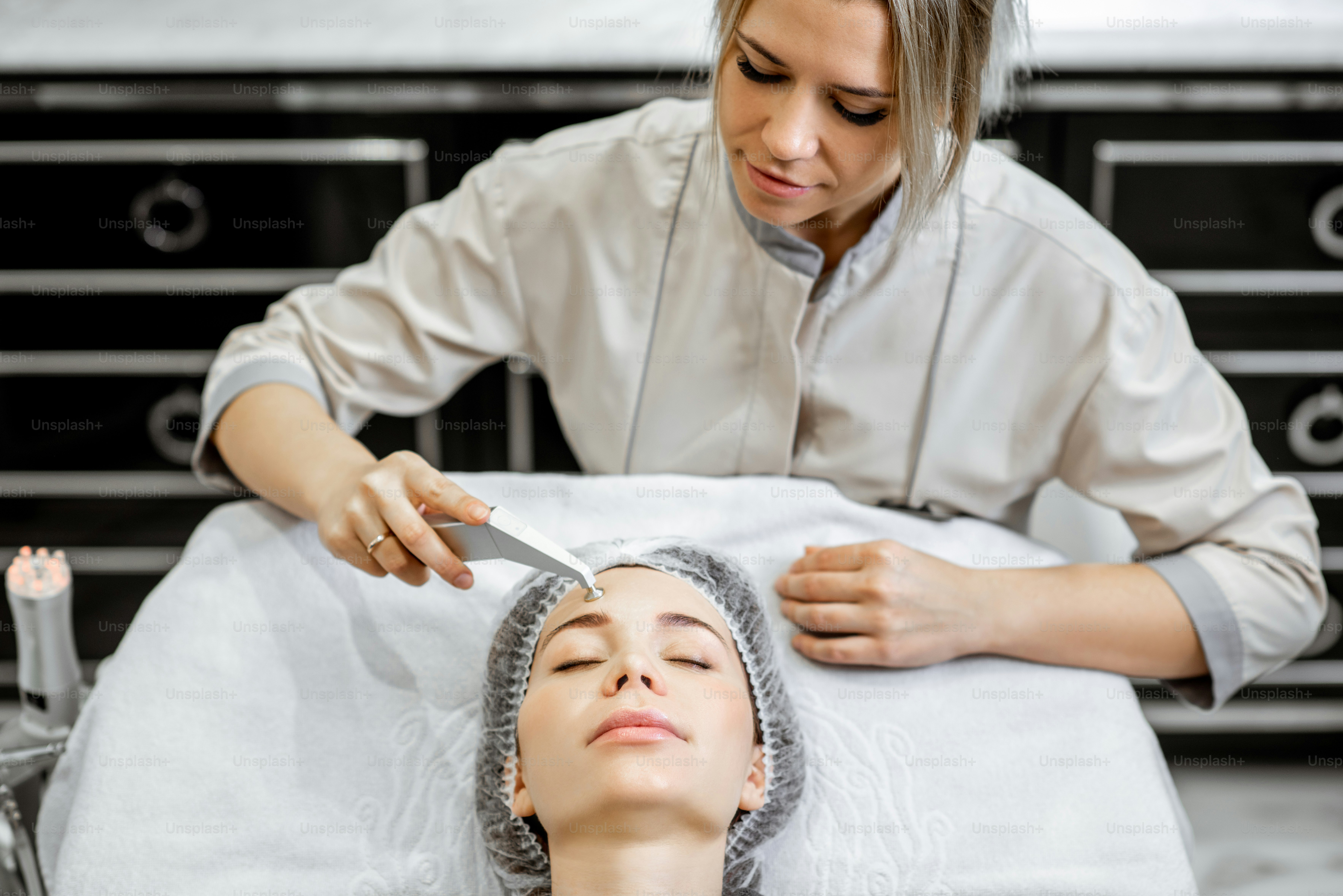Cosmetologist making vacuum hydro peeling on the cheek area to a woman ...