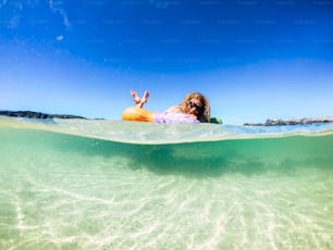 Turista alegre jovem mulher desfrutando de seu novo colchão inflável moderno na água do mar transparente em uma praia de areia durante as férias de verão - conceito de viagem e estilo de vida