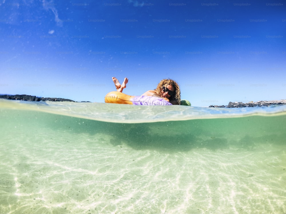 Mujer joven alegre de la gente del turista que disfruta de su nuevo colchón inflable de moda en el agua de mar transparente en una playa de arena durante las vacaciones de verano - concepto de viaje y estilo de vida