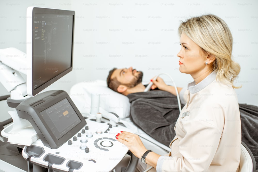 여성 의사는 진료실에서 남성 갑상선의 초음파 검사를 수행합니다. 남성 건강의 초음파 진단의 개념