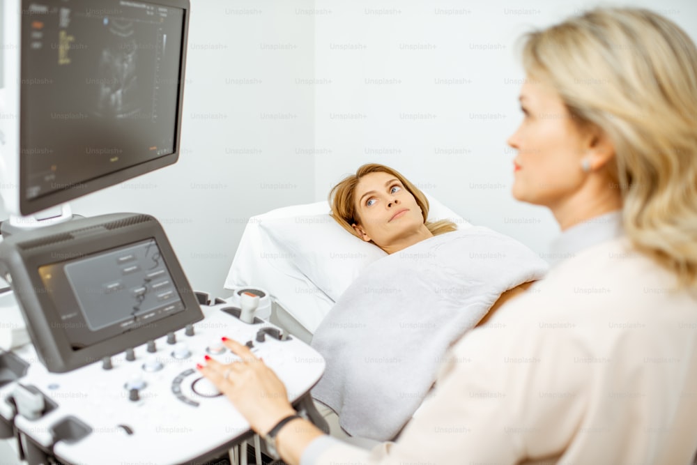 여성 의사는 여성 골반 장기의 초음파 검사를 수행하거나 진료실에서 임신 초기를 진단합니다.