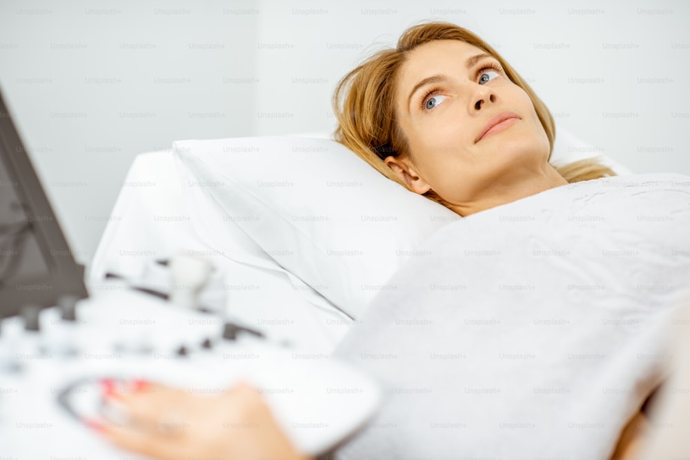 Donna che esamina i suoi organi pelvici con un sensore a ultrasuoni o diagnostica una gravidanza precoce presso lo studio medico. Concetto di diagnostica ecografica della salute femminile