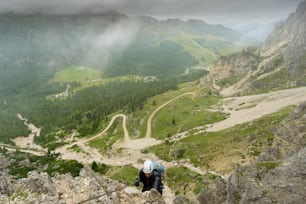 atractiva joven alpinista en una vía ferrata en los Dolomitas de Italia con mal tiempo
