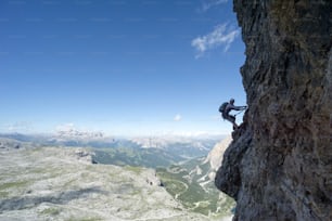 Horizontal view of an attractive female climber on a steep Via Ferrata in the Italian Dolomites with a great view behind