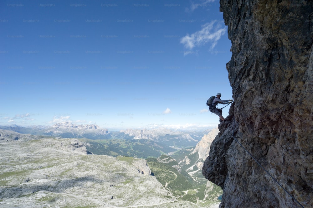 Vista horizontal de uma atraente alpinista feminina em uma íngreme Via Ferrata nas Dolomitas italianas com uma excelente vista atrás