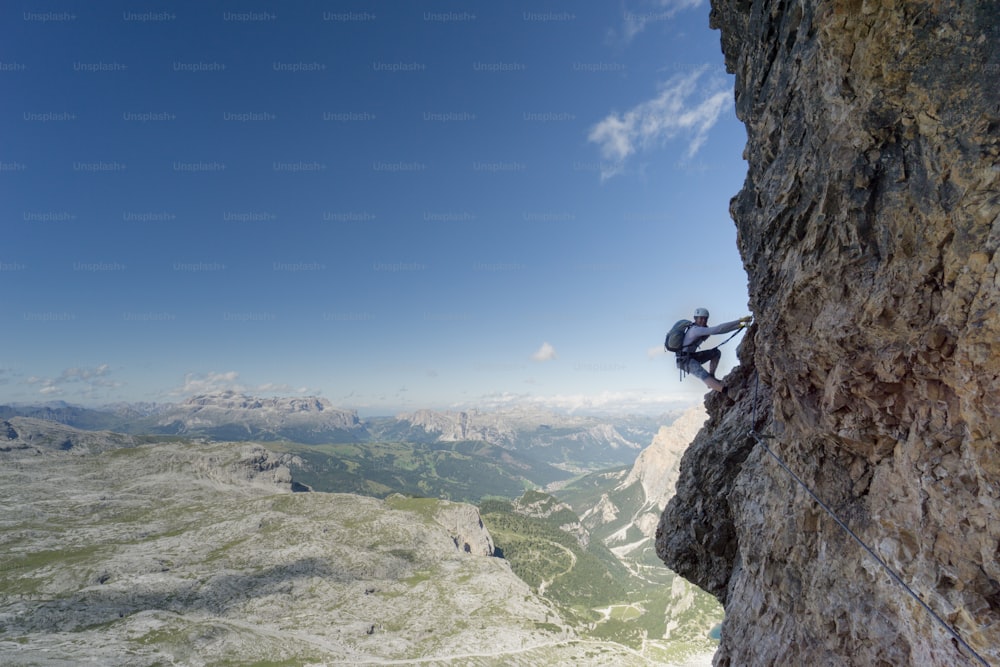 Vista horizontal de uma atraente alpinista feminina em uma íngreme Via Ferrata nas Dolomitas italianas com uma excelente vista atrás