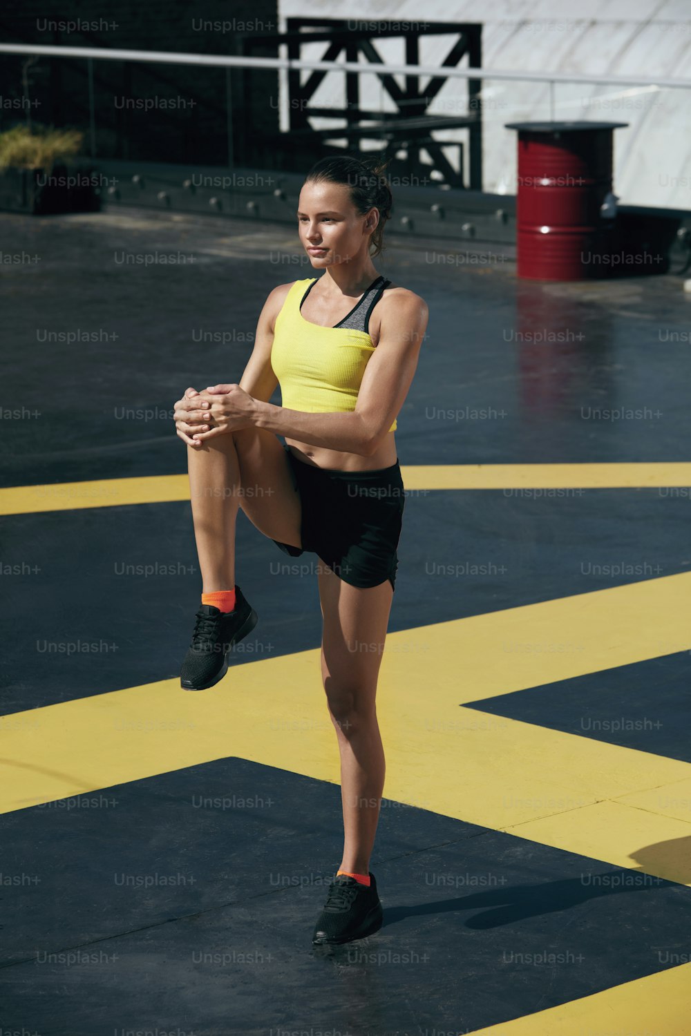 Mujer fitness en ropa deportiva estirando las piernas antes de entrenar al aire libre. Retrato de cuerpo entero de la muchacha en forma en ropa deportiva calentando en la calle