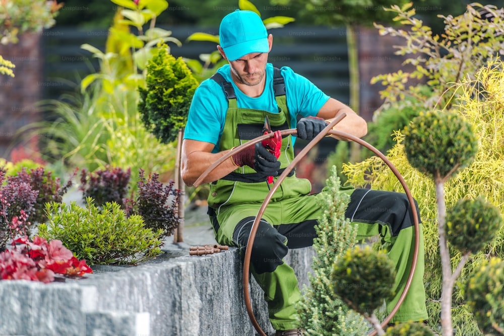 Quarante ans hommes caucasiens bâtiment jardin irrigation système d’arrosage. Technologies de l’aménagement paysager et du jardin.