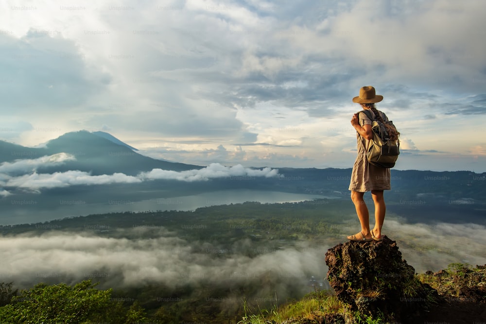 Woman enjoying sunrise from a top of mountain Batur, Bali, Indonesia.