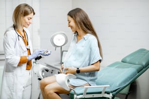 Ginecólogo administrando un medicamento a una joven embarazada durante un examen médico en el consultorio. Concepto de tomar medicamentos durante el embarazo