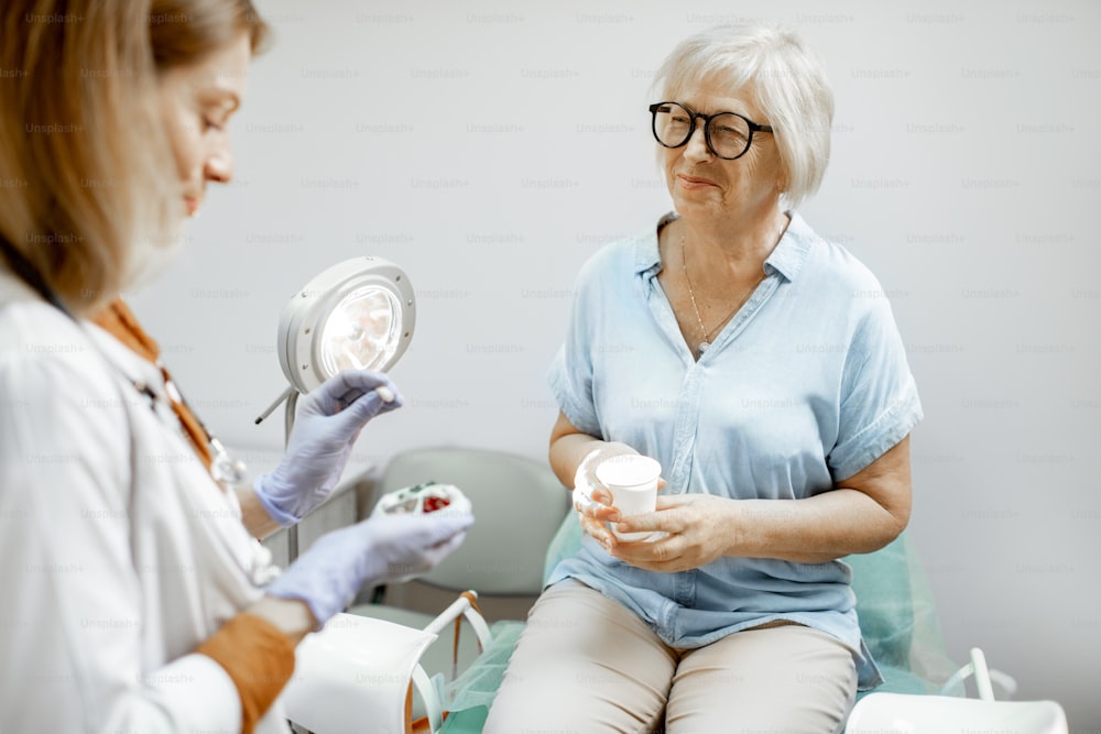 Mujer mayor sentada en la silla ginecológica durante una consulta médica con el ginecólogo. Doctor dando algunos medicamentos